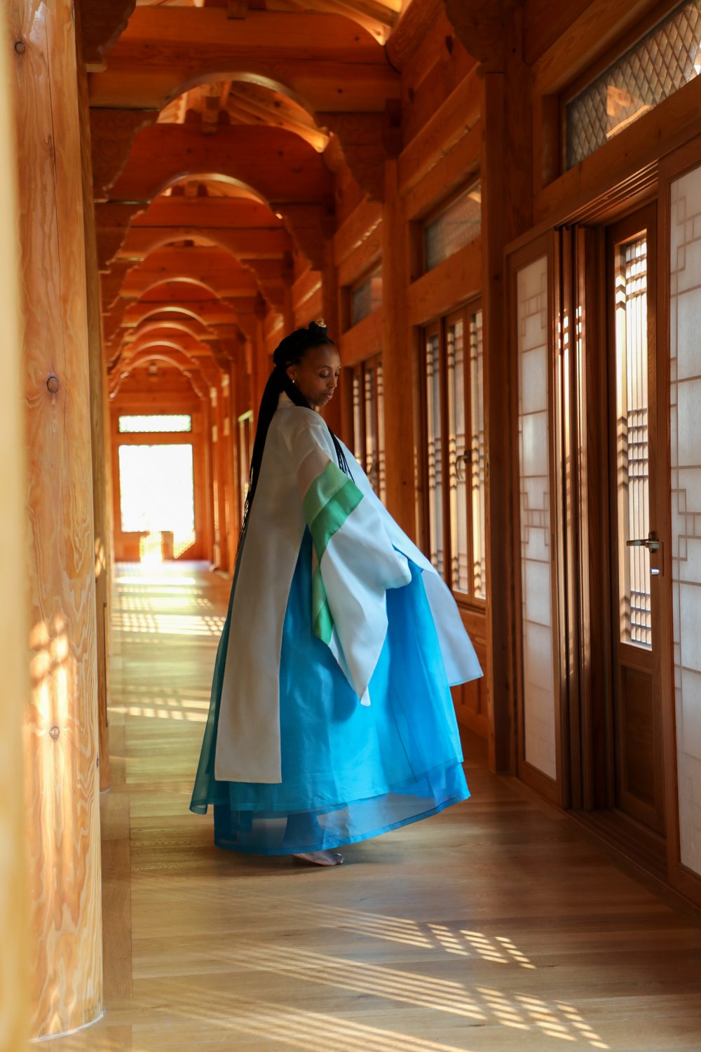 Hanbok in a sunlit timber corridor