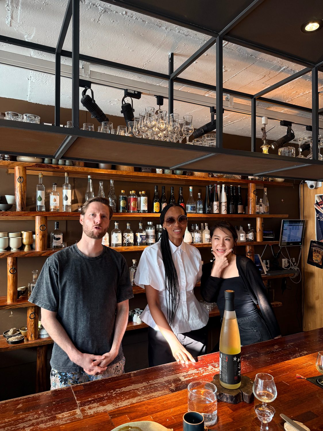 Dustin Wessa behind the bar, beneath shelves of Korean sool